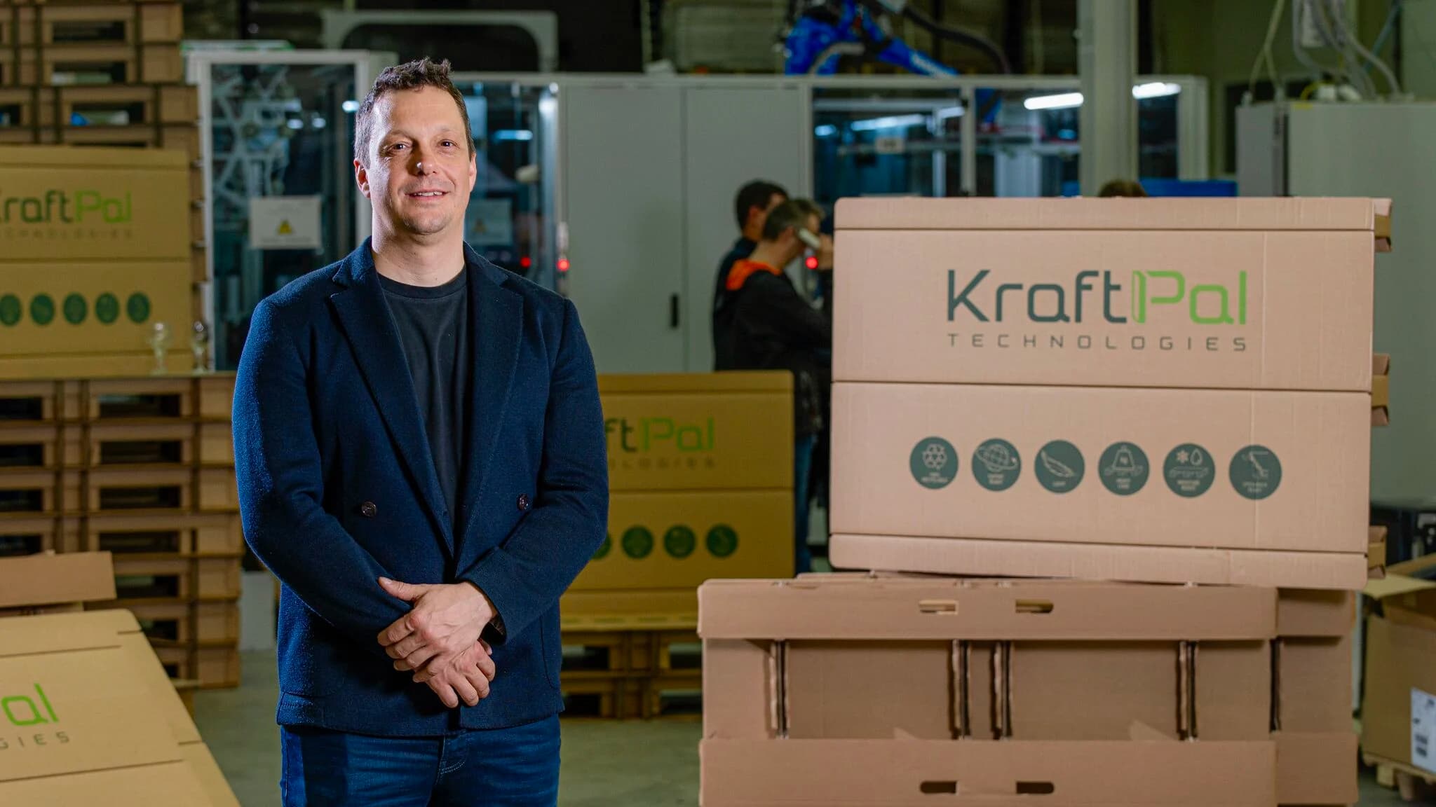 Gregor Brajovic standing in a KraftPal facility beside corrugated packaging