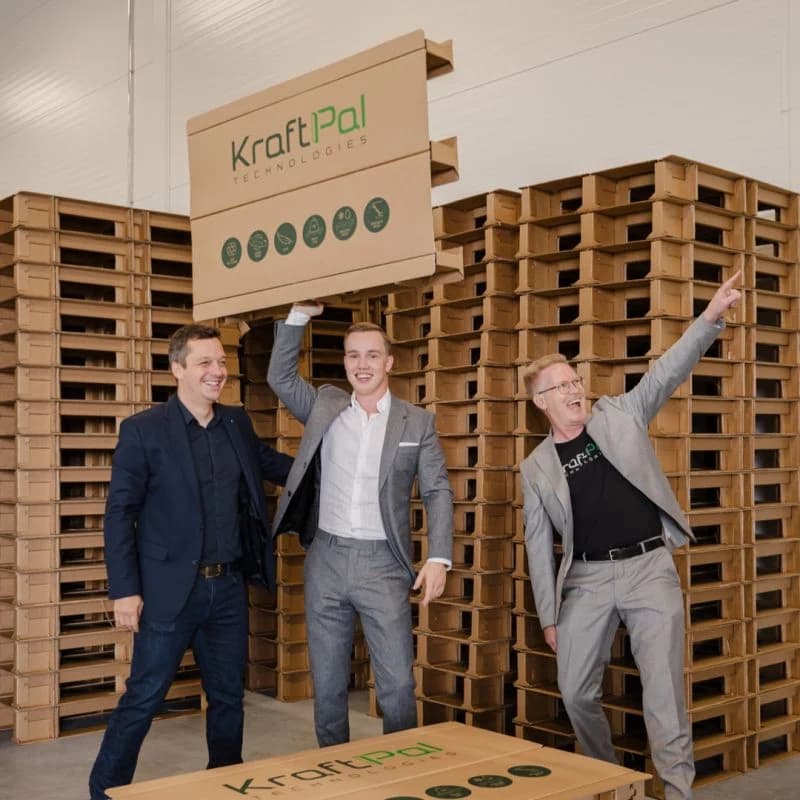 KraftPal founders celebrating beside corrugated pallets and packaging